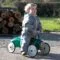 Boy riding the Vilac Classic Car Racing Green in front of log pile