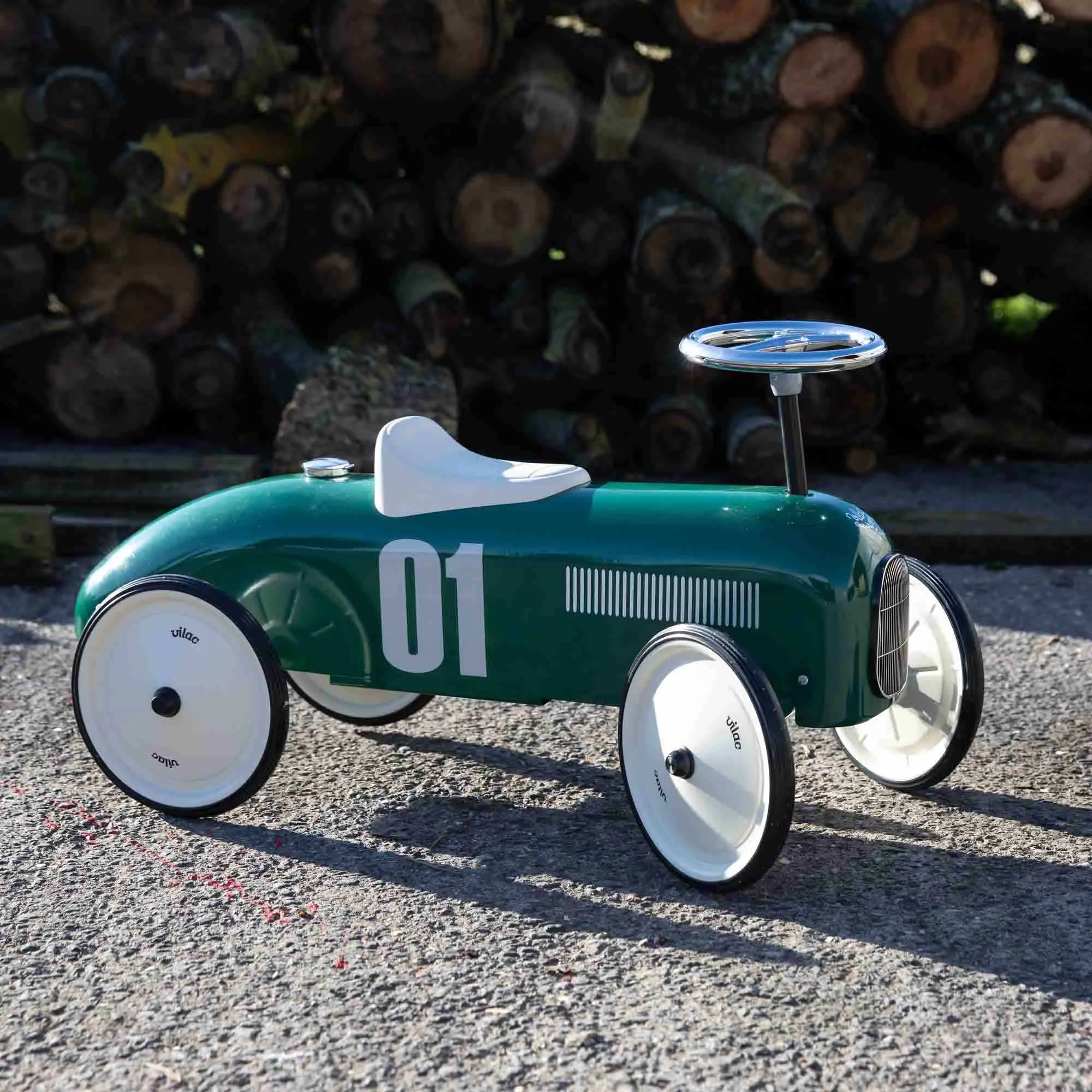 Vilac Racing Green Classic Car in front of log pile