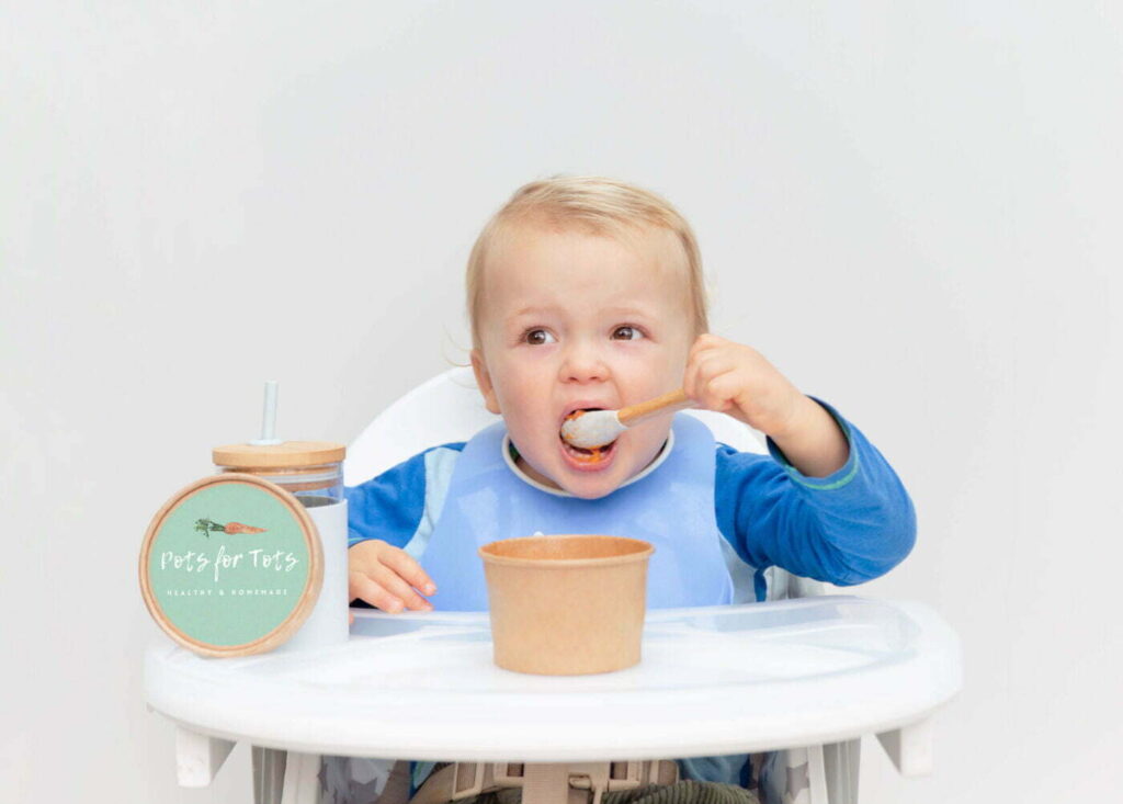 Little boy eating from a little cardboard takeaway pot
