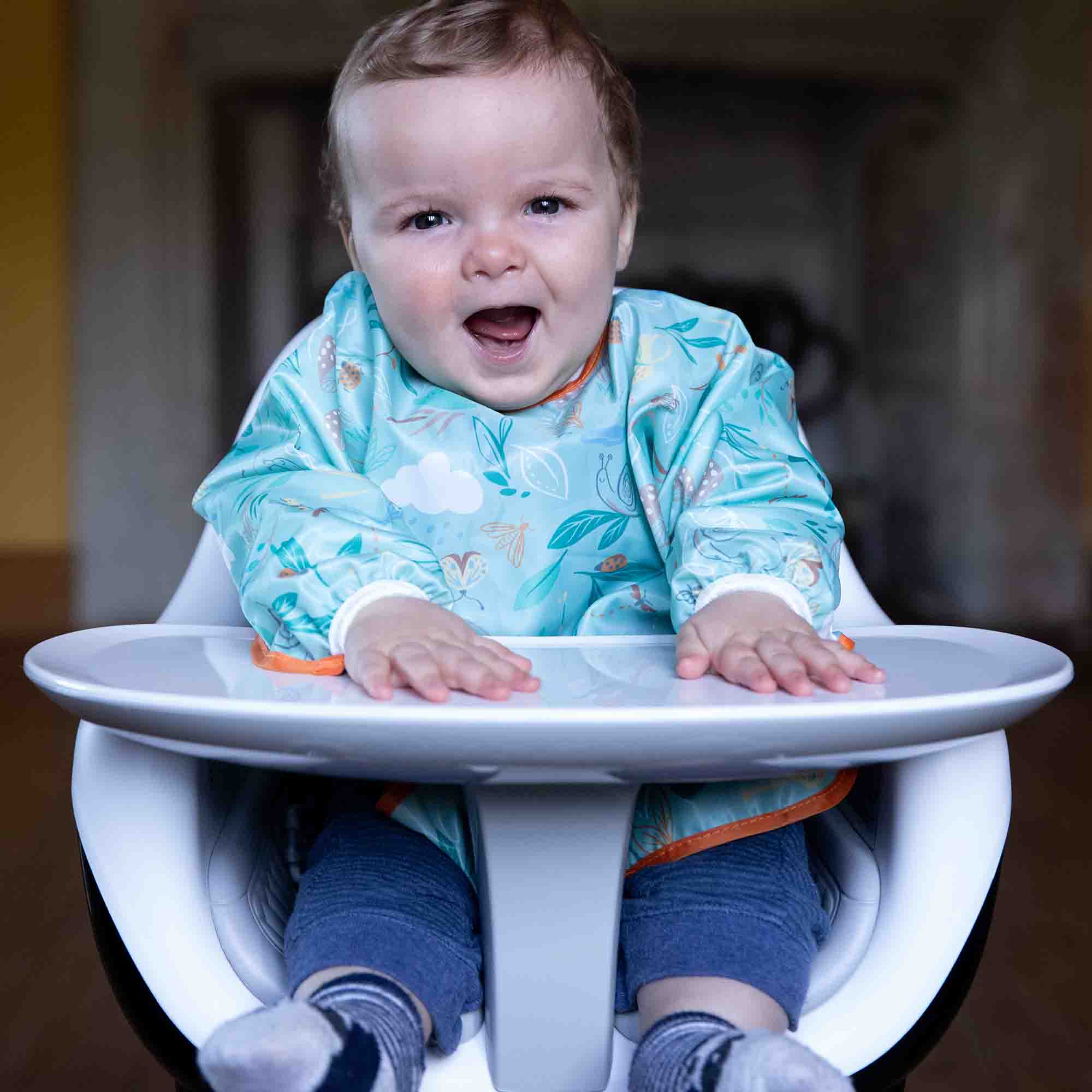Bumbo Highchair with little boy sat in it smiling, wearing a Hippychick Bib