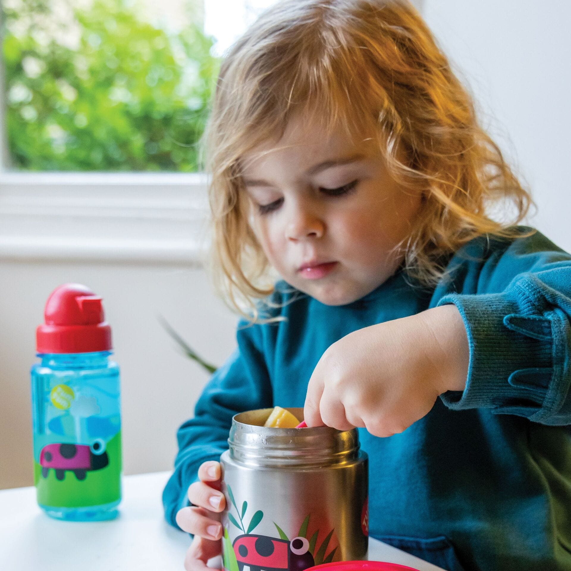 Child scooping food out of the ladybird food flask