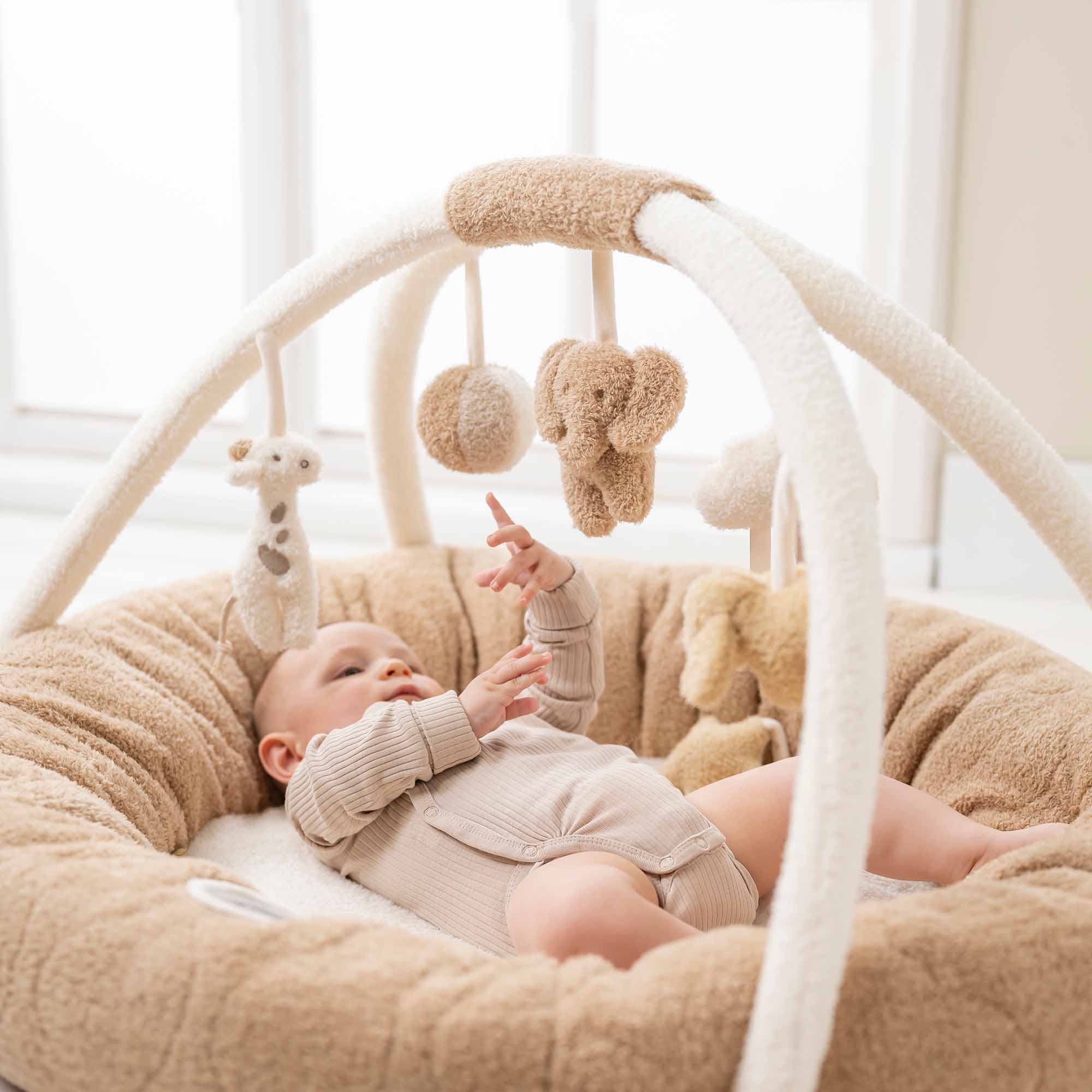 Baby playing with Stuffed teddy playmat with arches