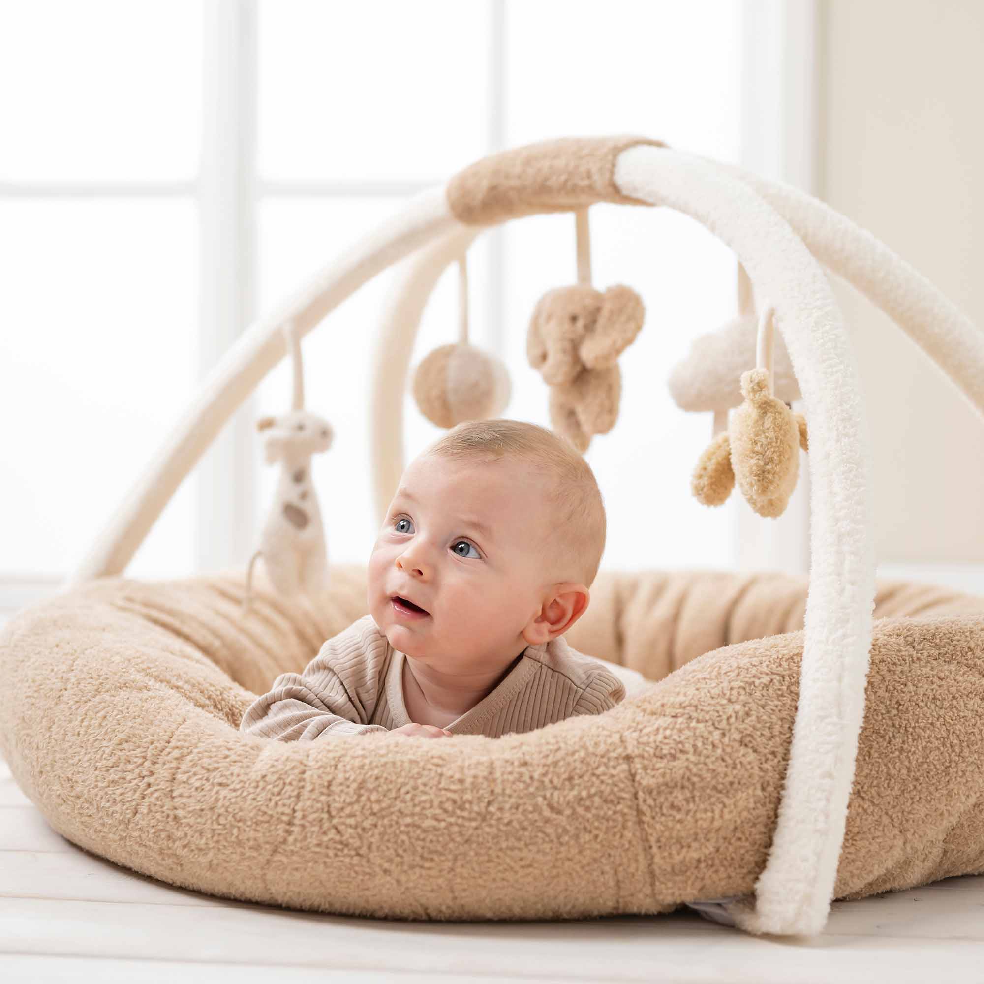 Baby playing with Stuffed teddy playmat with arches