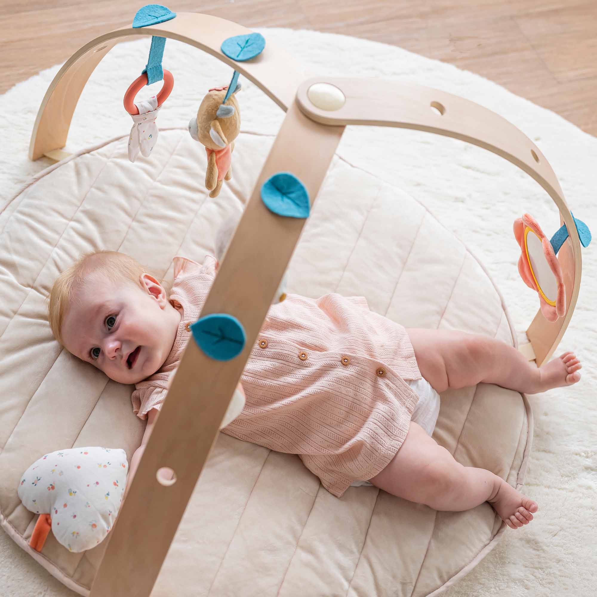Baby lying under the arch playing with the toys