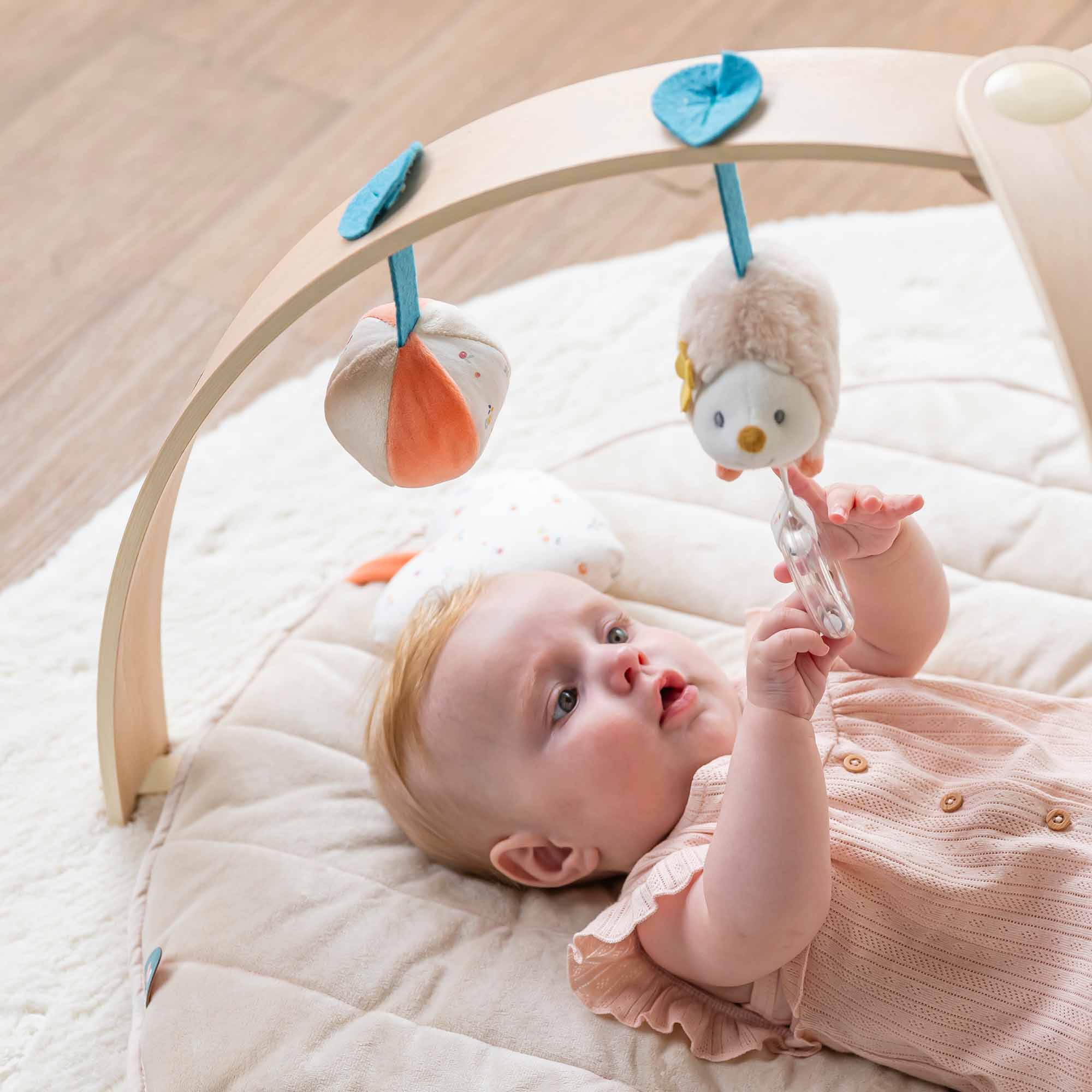 Baby lying under the arch playing with the toys
