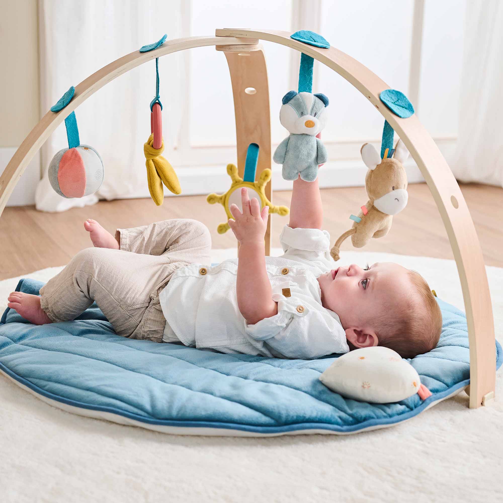 Baby playing under the wooden arches pointing to toys