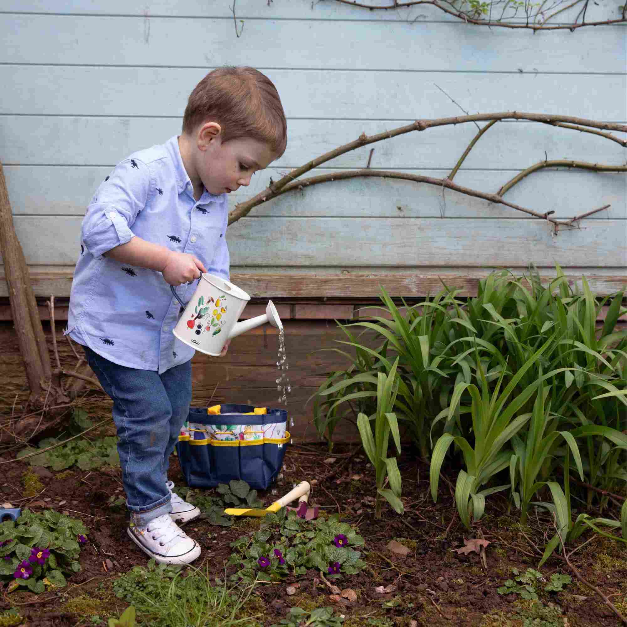 Boy holding the watering can with the bag in the background