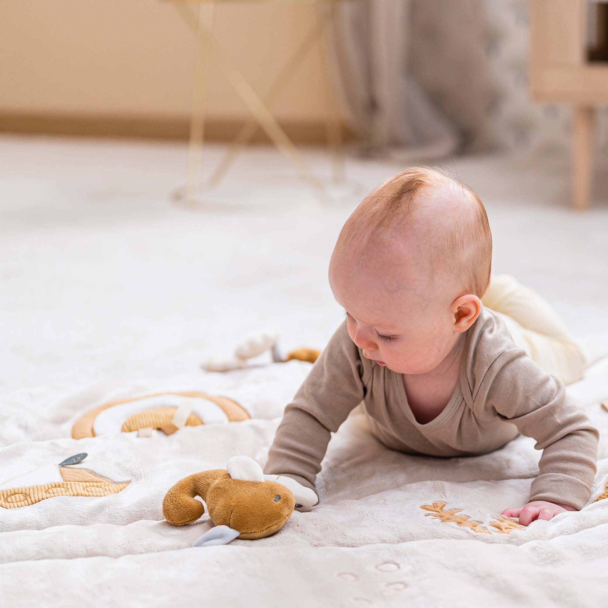 Baby playing on the Nattou Activity Mat lying on their tummy