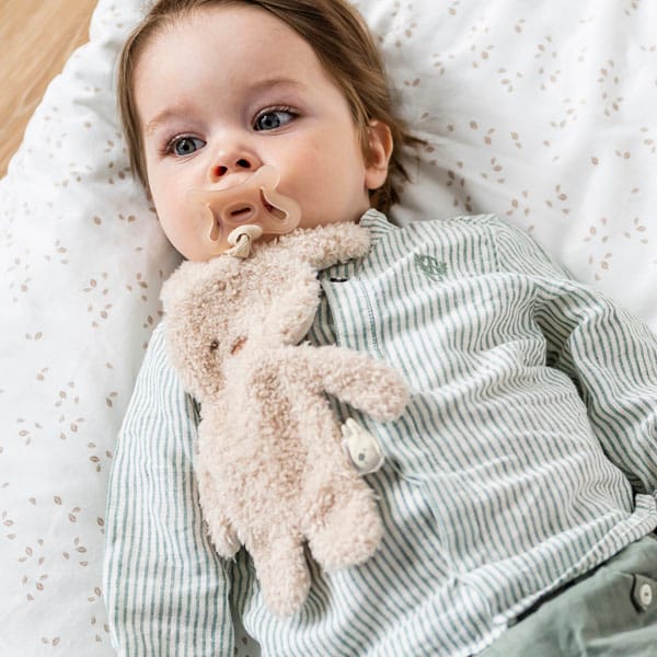 Child with the DouDou Pacifier Bunny attached to their dummy