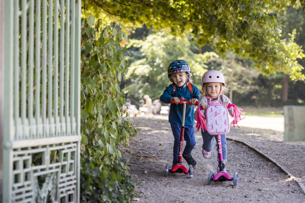 children playin outisde on micro scooter